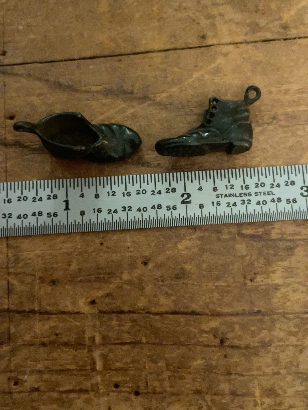 Vintage miniature metal boot charms shown beside ruler for scale