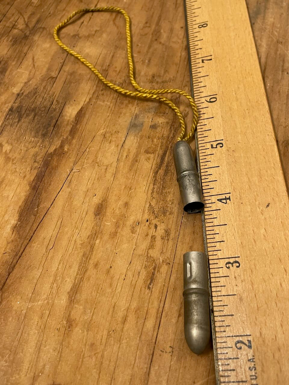 Metal pencil toppers and a wooden ruler on a wooden surface (pencil toppers slightly more than 1" long).