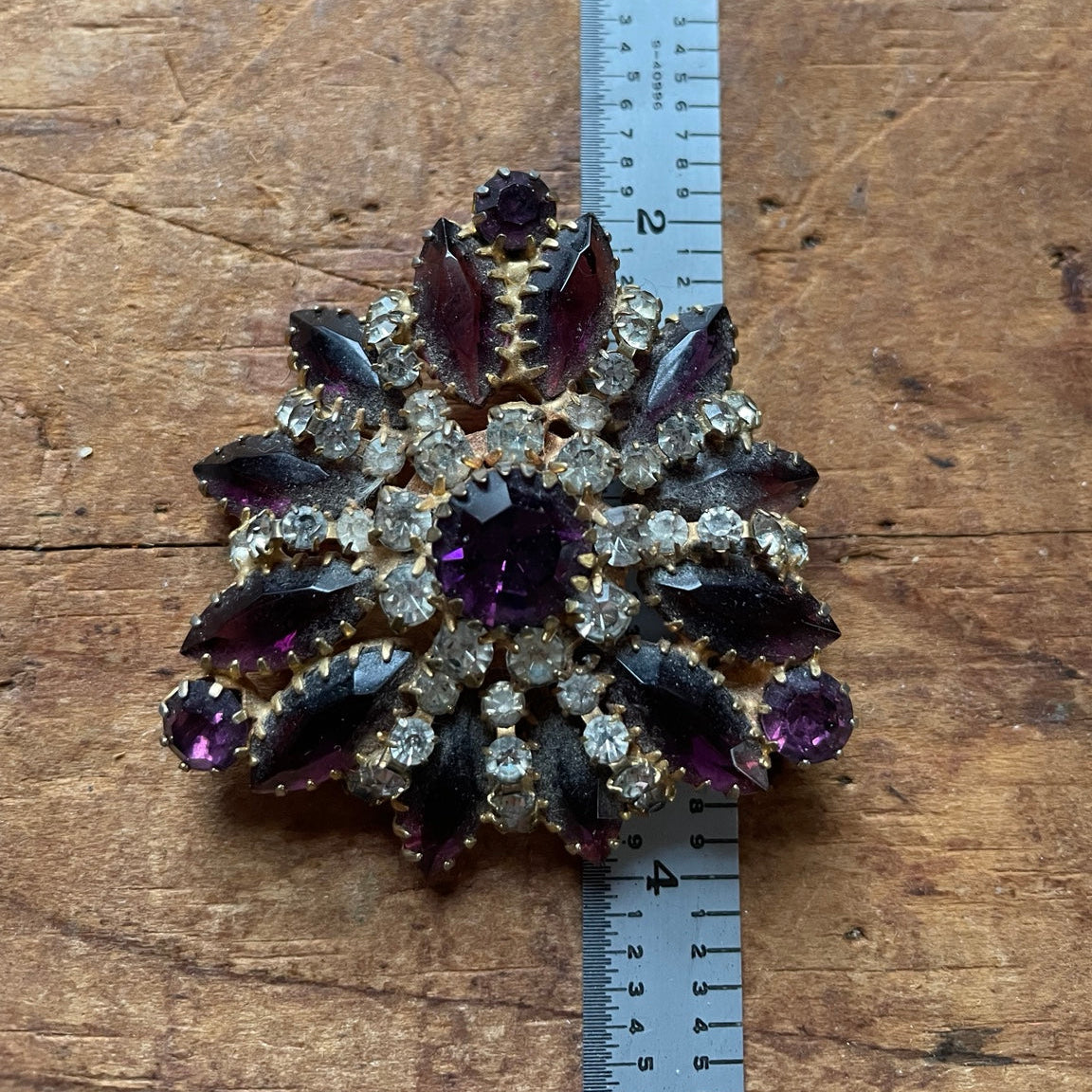 Vintage purple glass rhinestone cluster brooch shown from the front with ruler