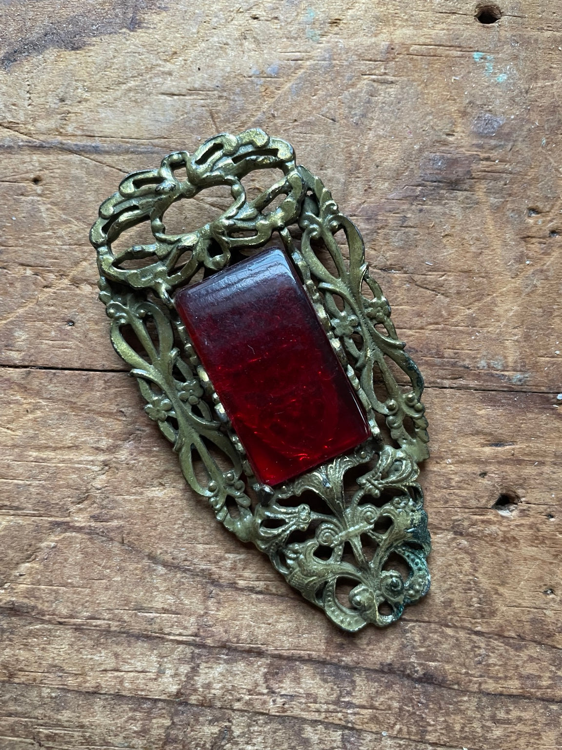 Vintage Art Deco red glass cabochon brooch in ornate pierced gold-tone setting, front view