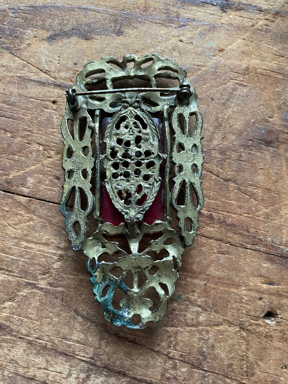 Back of vintage red glass brooch showing openwork setting and pin clasp