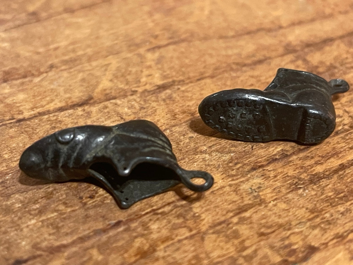Undersides of miniature metal boot charms showing molded sole and tread detail