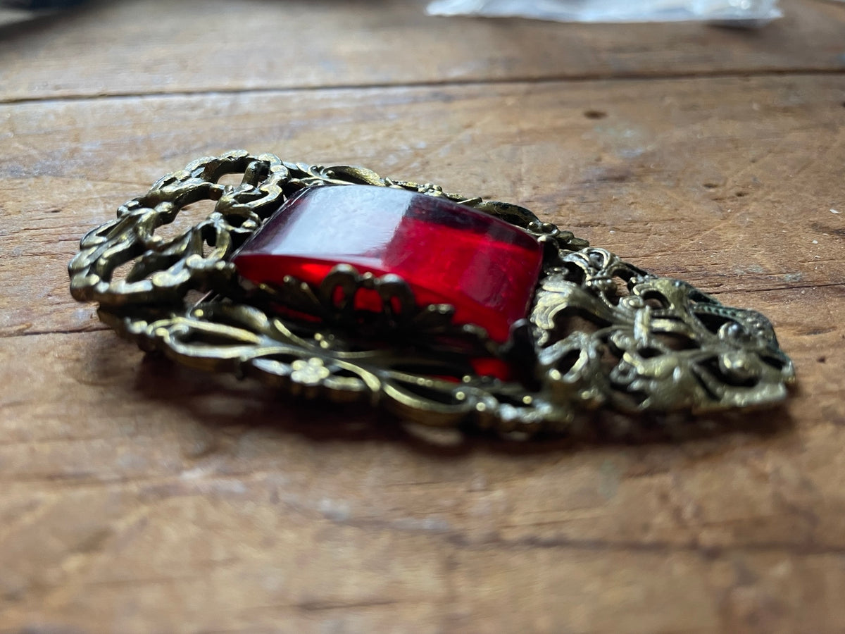 Side profile of vintage red glass cabochon brooch showing raised setting