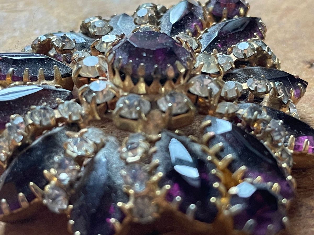 Close-up of purple glass stones and clear rhinestones in gold-tone settings