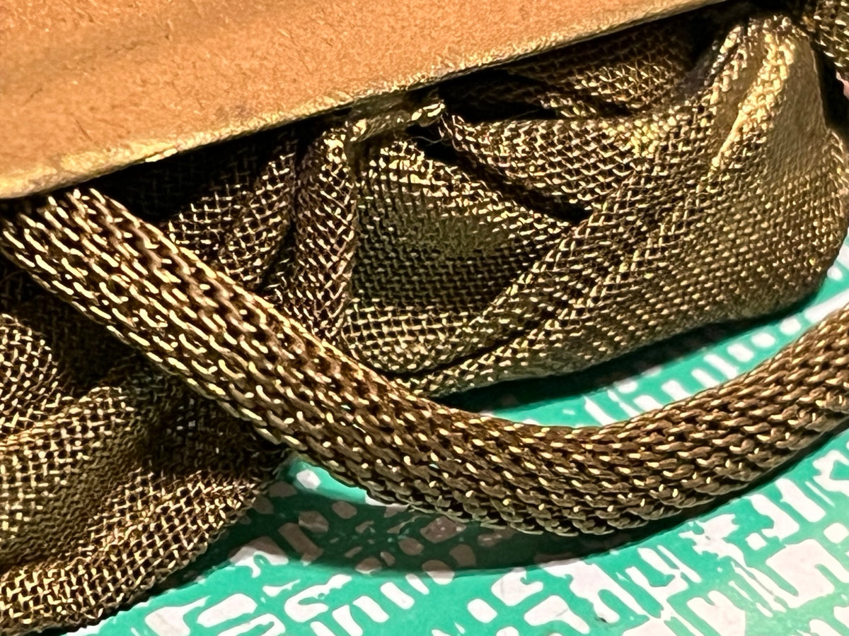 Close detail of tubular woven metal mesh construction on vintage rose brooch