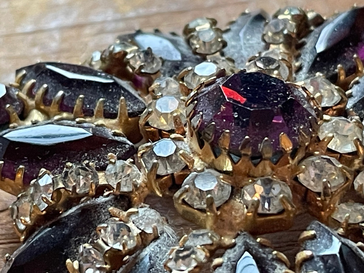 Back of purple rhinestone cluster brooch showing open-backed stone settings and construction