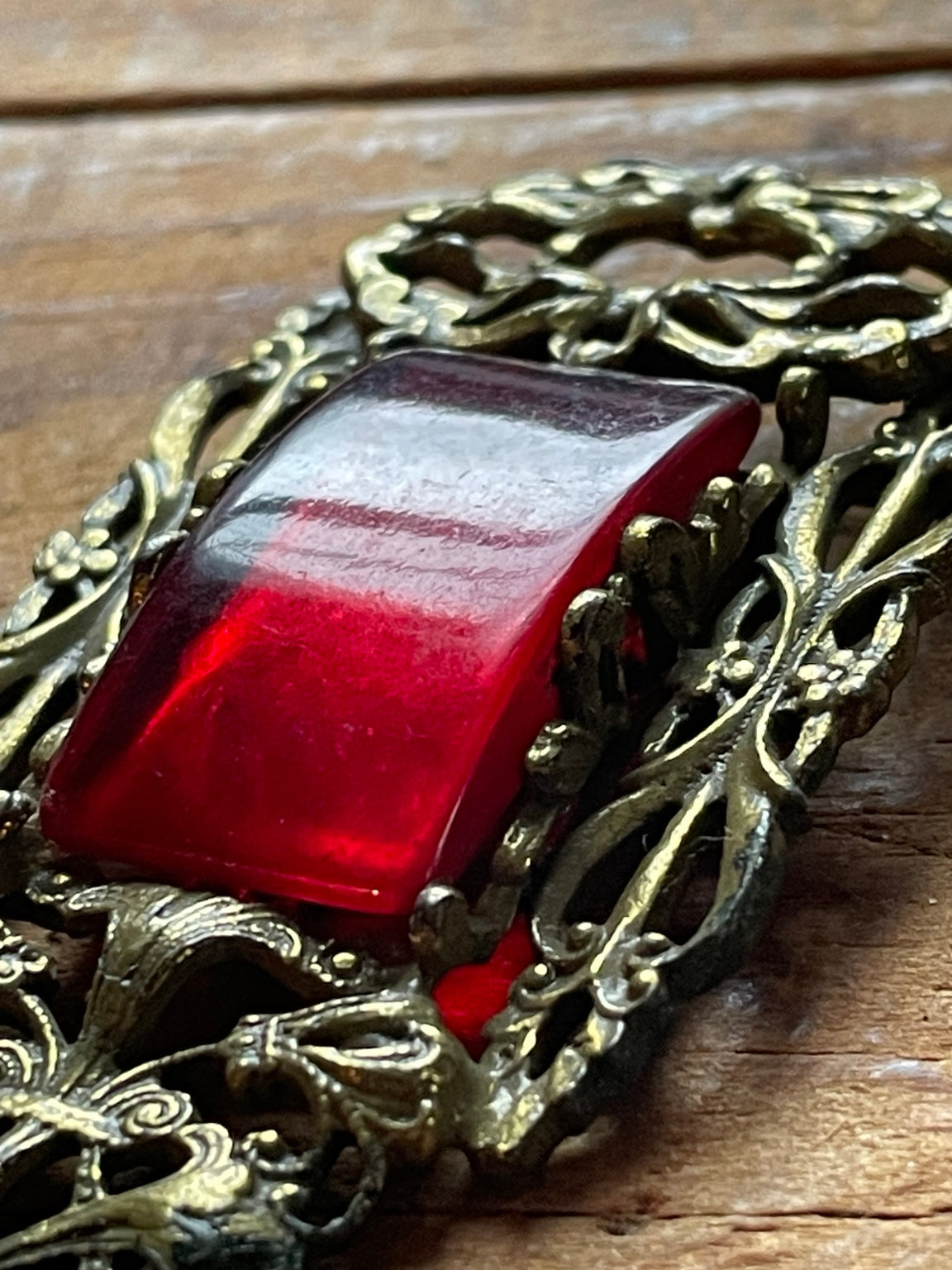 Close-up of translucent red glass cabochon in ornate pierced setting