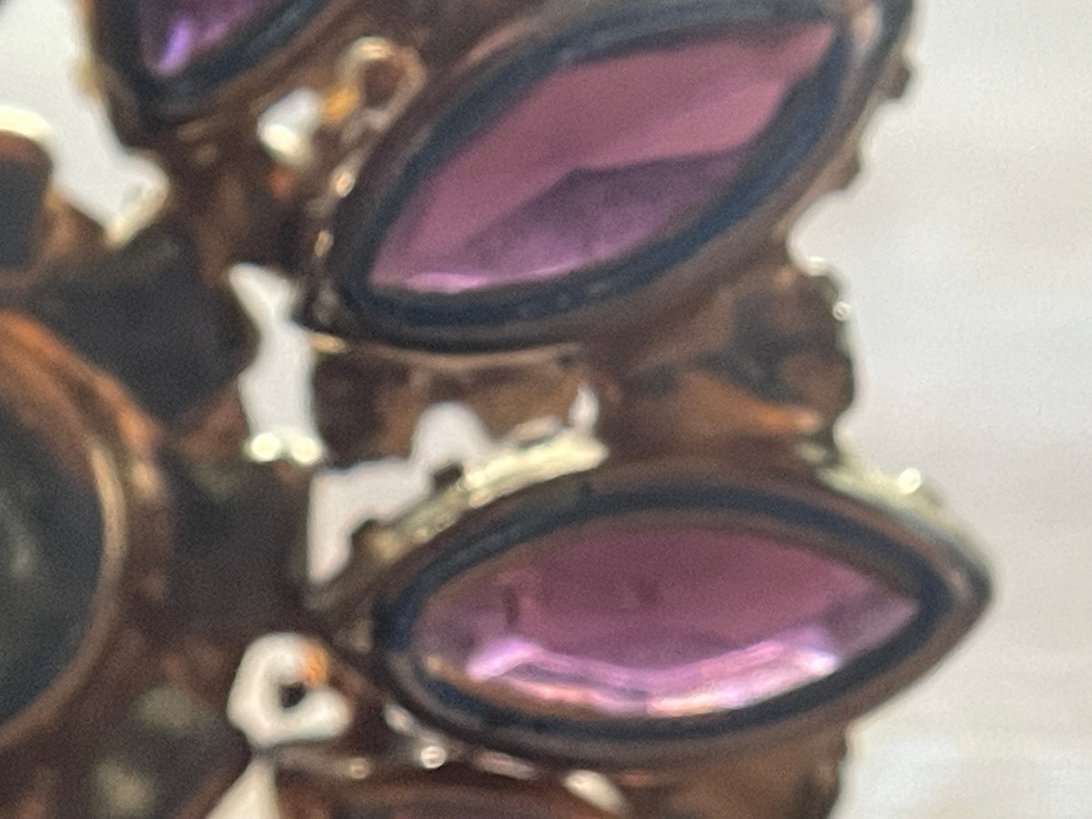 Close-up of purple glass and clear rhinestones showing age-related surface wear