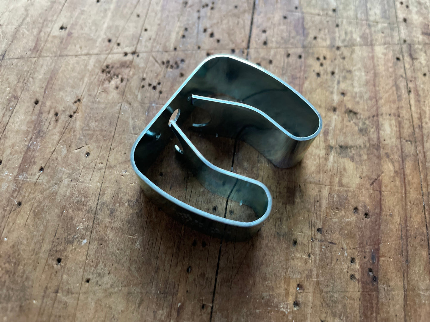 Metal broom holder (vintage) on a wooden surface
