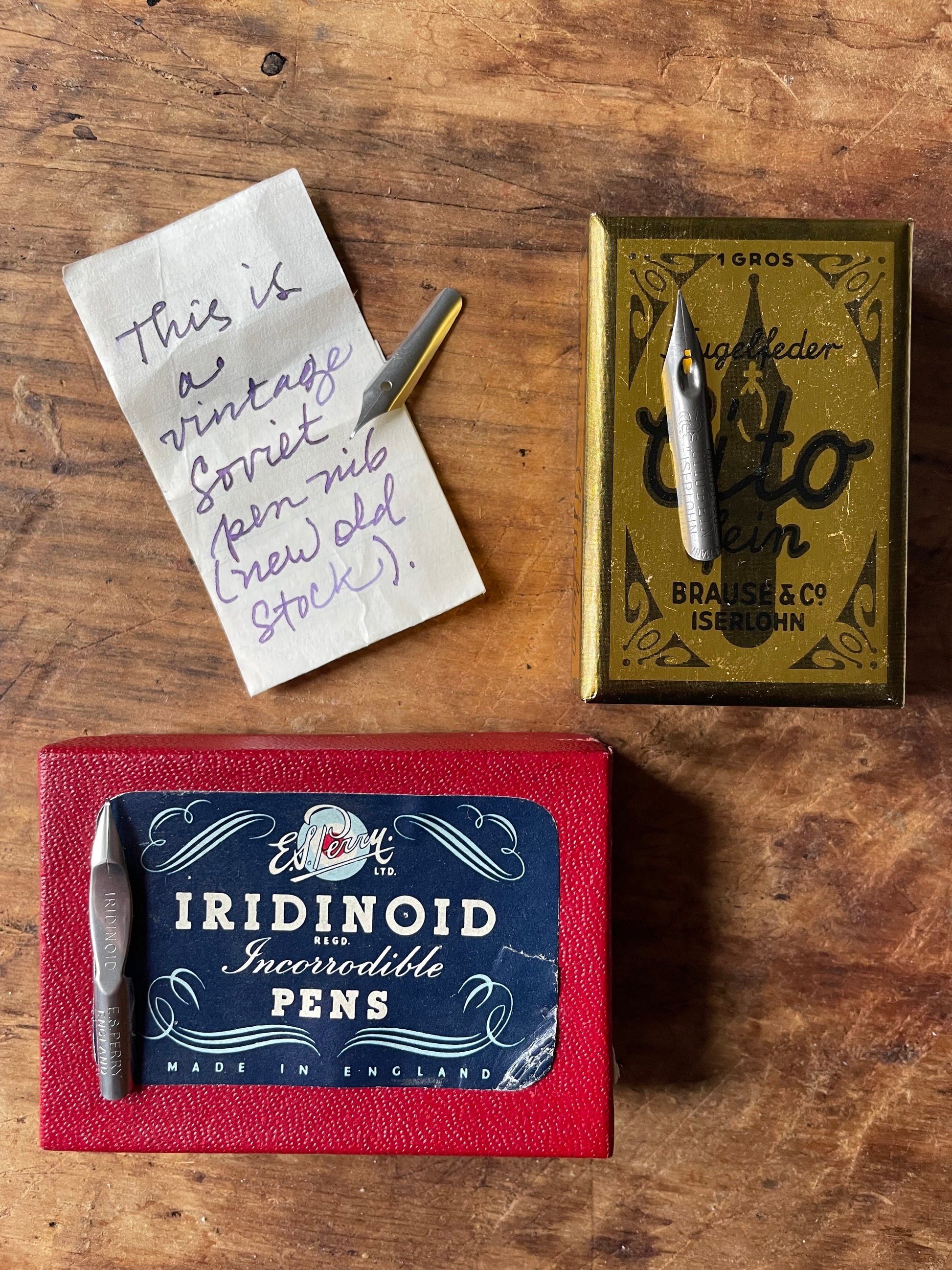 Three writing nibs with their original vintage packaging against a wooden surface