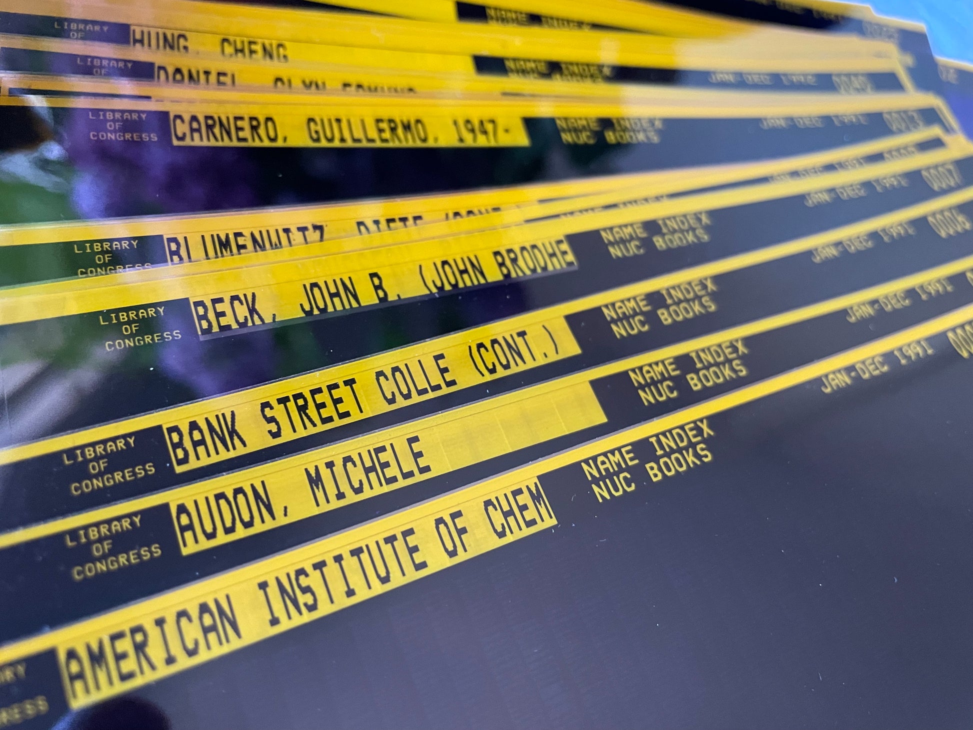 Color-sorted (in this photo, gold-trimmed) vintage microfiche film sheets photographed in natural light.