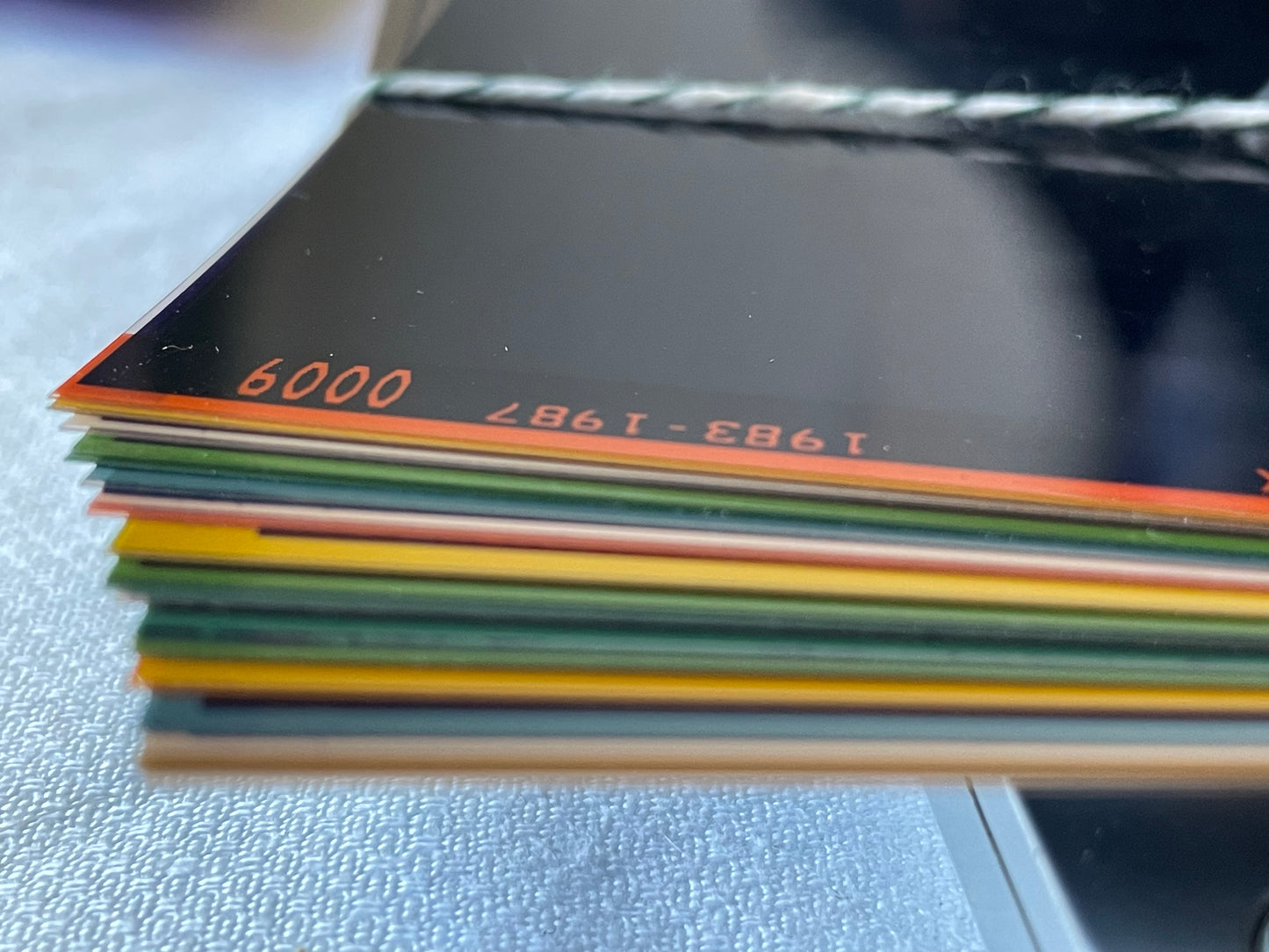 Tied bundle of translucent vintage microfiche sheets in assorted archival colors against a white surface.