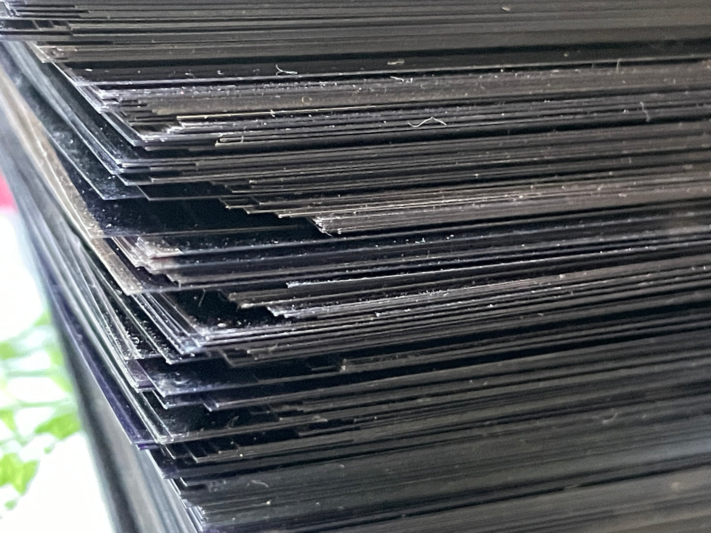 Close-up stack of microfiche against green and white surface; dust motes visible on fiche.