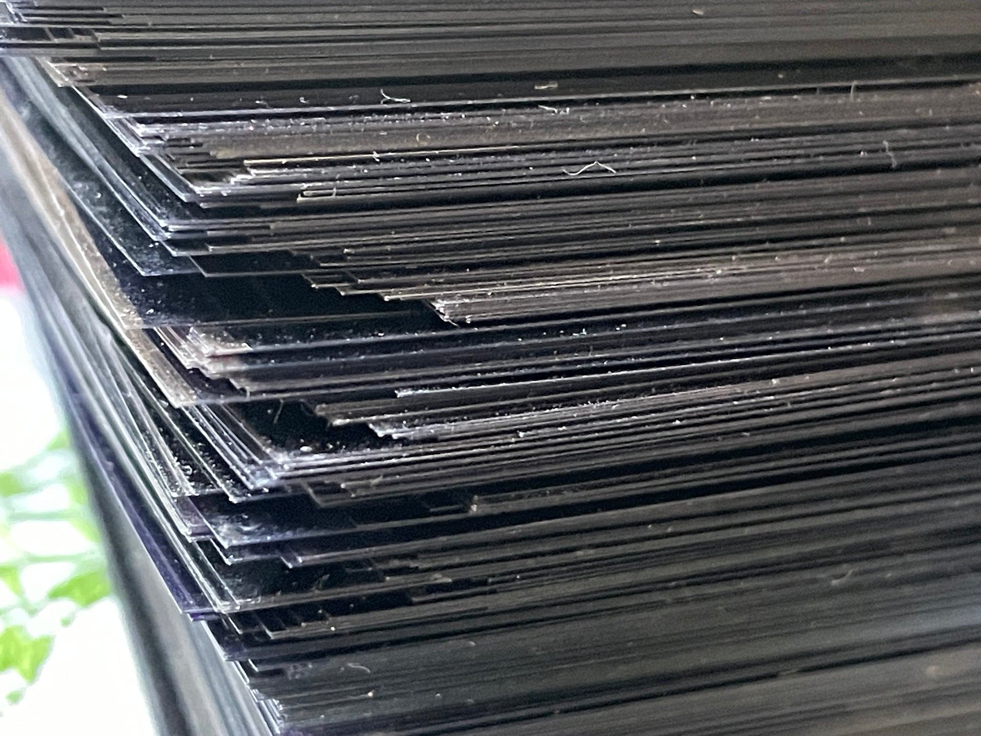 Close-up stack of microfiche against green and white surface; dust motes visible on fiche.