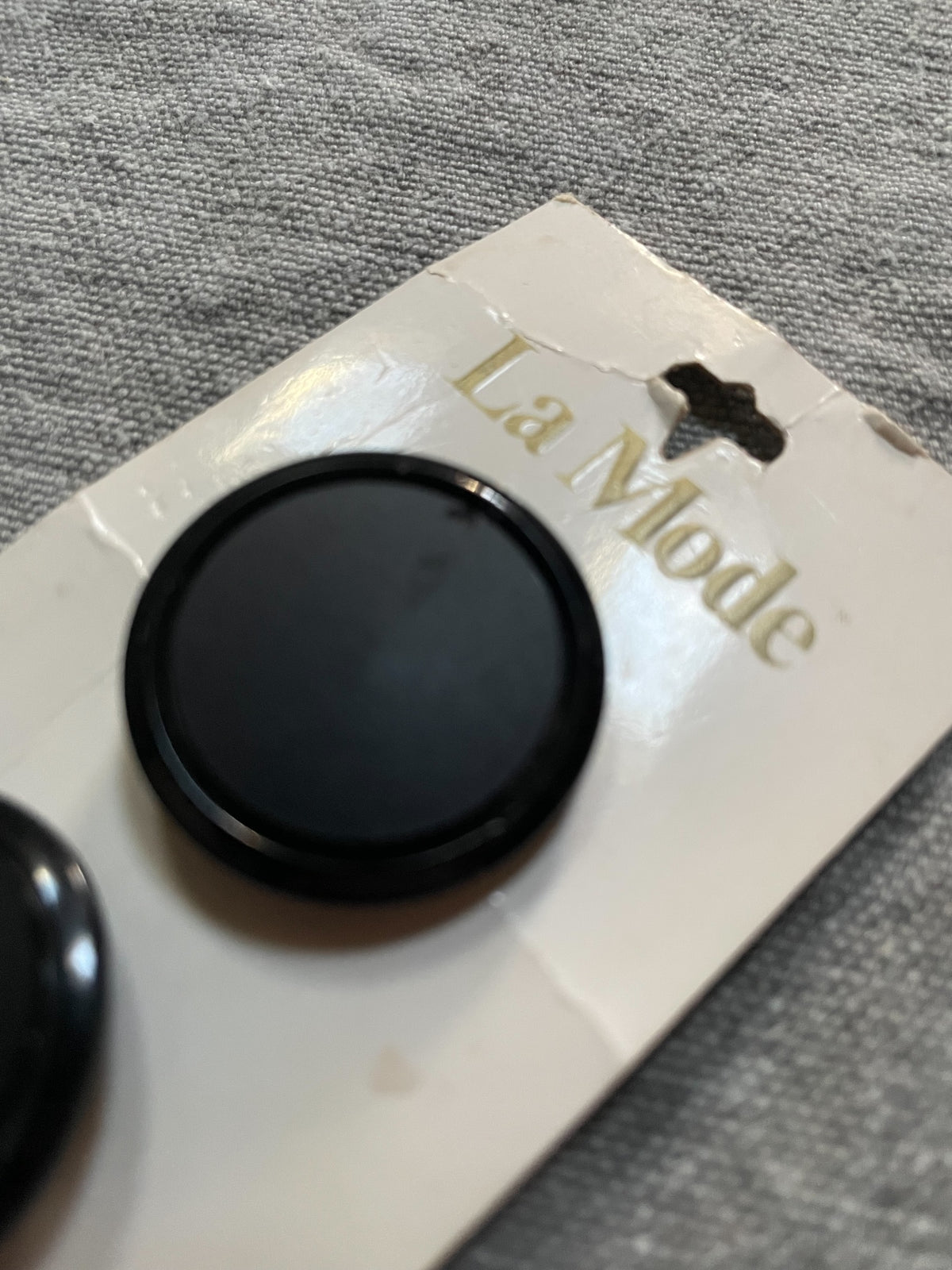 Close-up detail of 2 black la mode sewing buttons, 1 1/8 inch, nos on original card