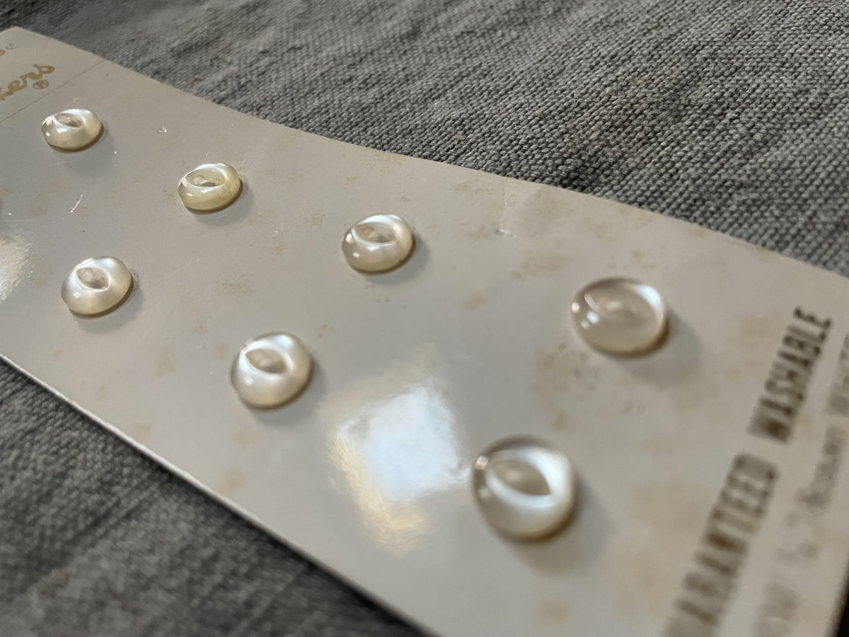 Close-up detail of 8 white costumakers sewing buttons, 7 mm, nos on original card