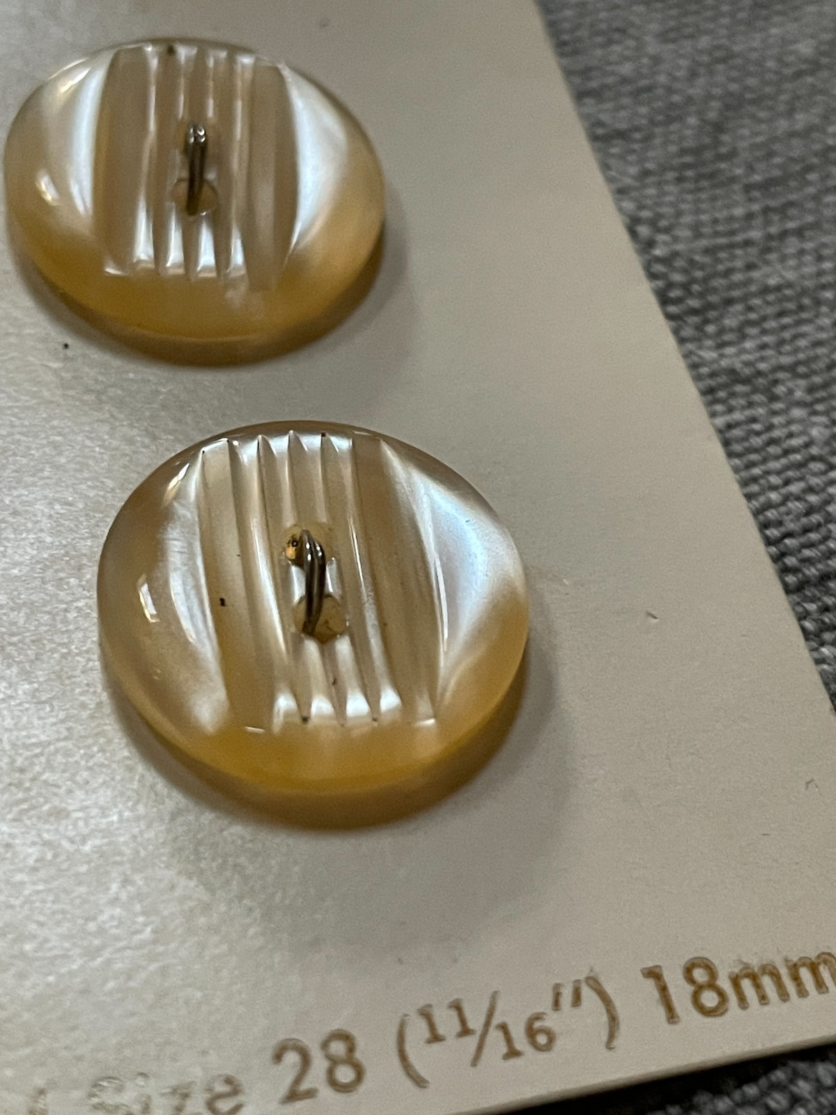 Close-up detail of 2 beige streamline two-hole sewing buttons, 18 mm, nos on card