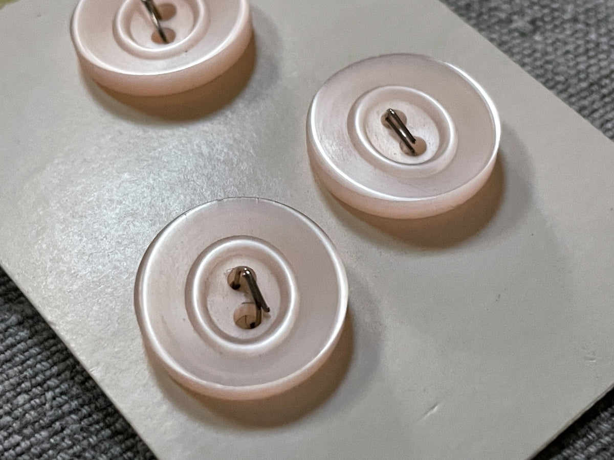 Close-up detail of 3 pale pink streamline two-hole sewing buttons, 15.46 mm, nos