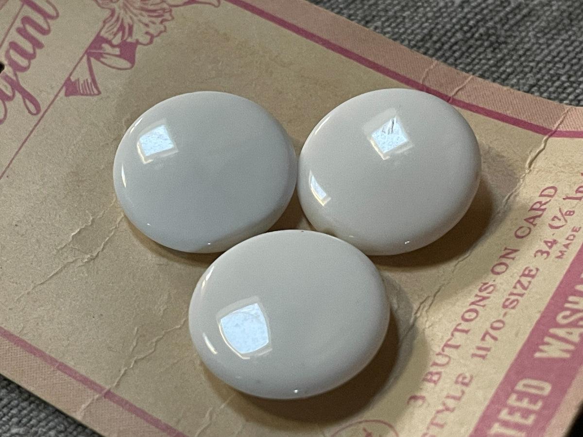Close-up detail of 3 white elegant sewing buttons, 7/8 inch, nos on original card
