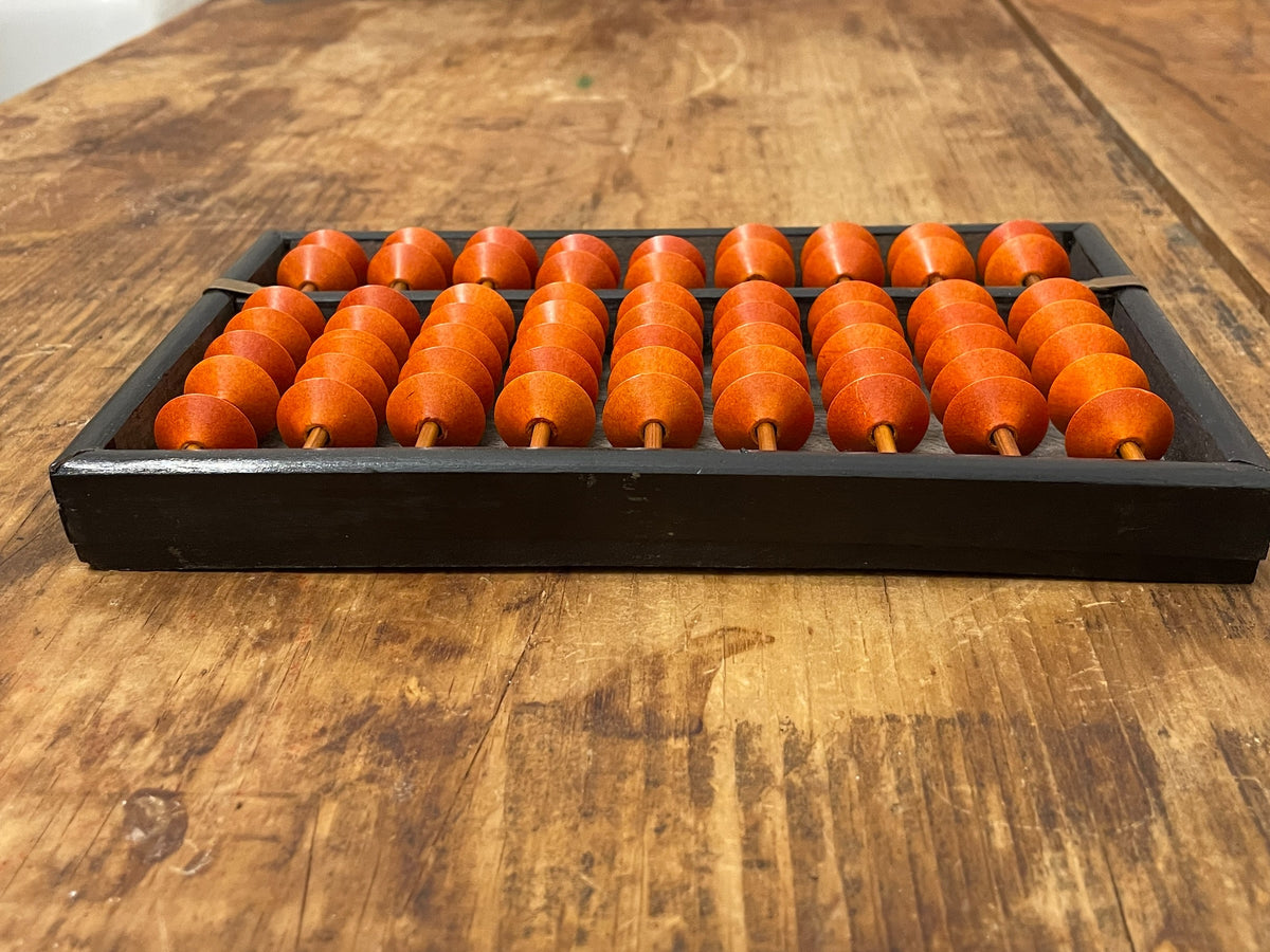 Low-angle view of vintage soroban abacus with orange beads in a black frame