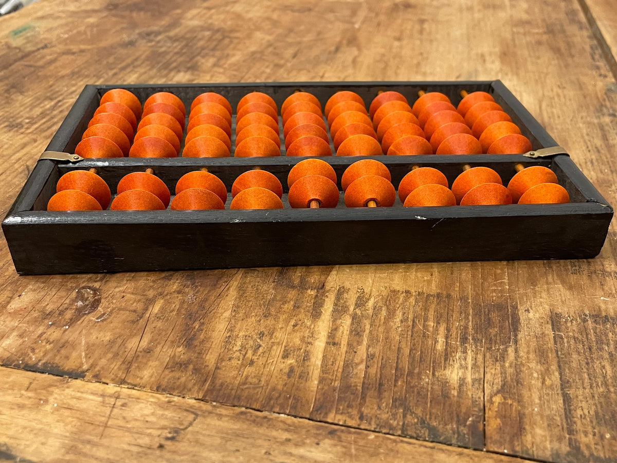 Angled view of orange beads and black frame on vintage soroban abacus