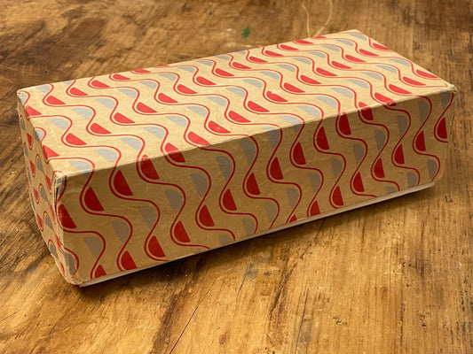 Angled view of vintage red, blue and cream paper-covered cardboard box
