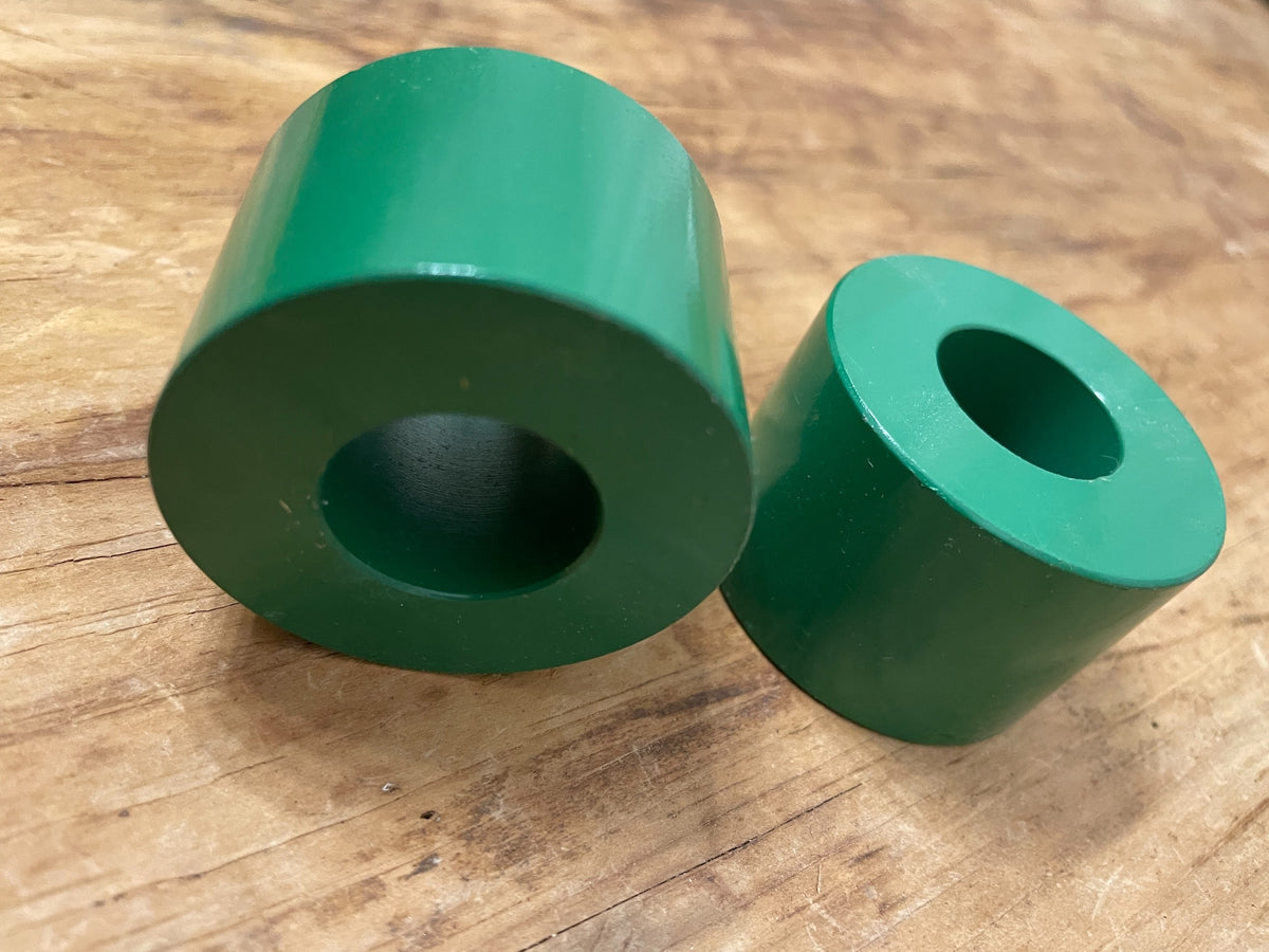 Angled close-up of two green modernist cylinder candle holders