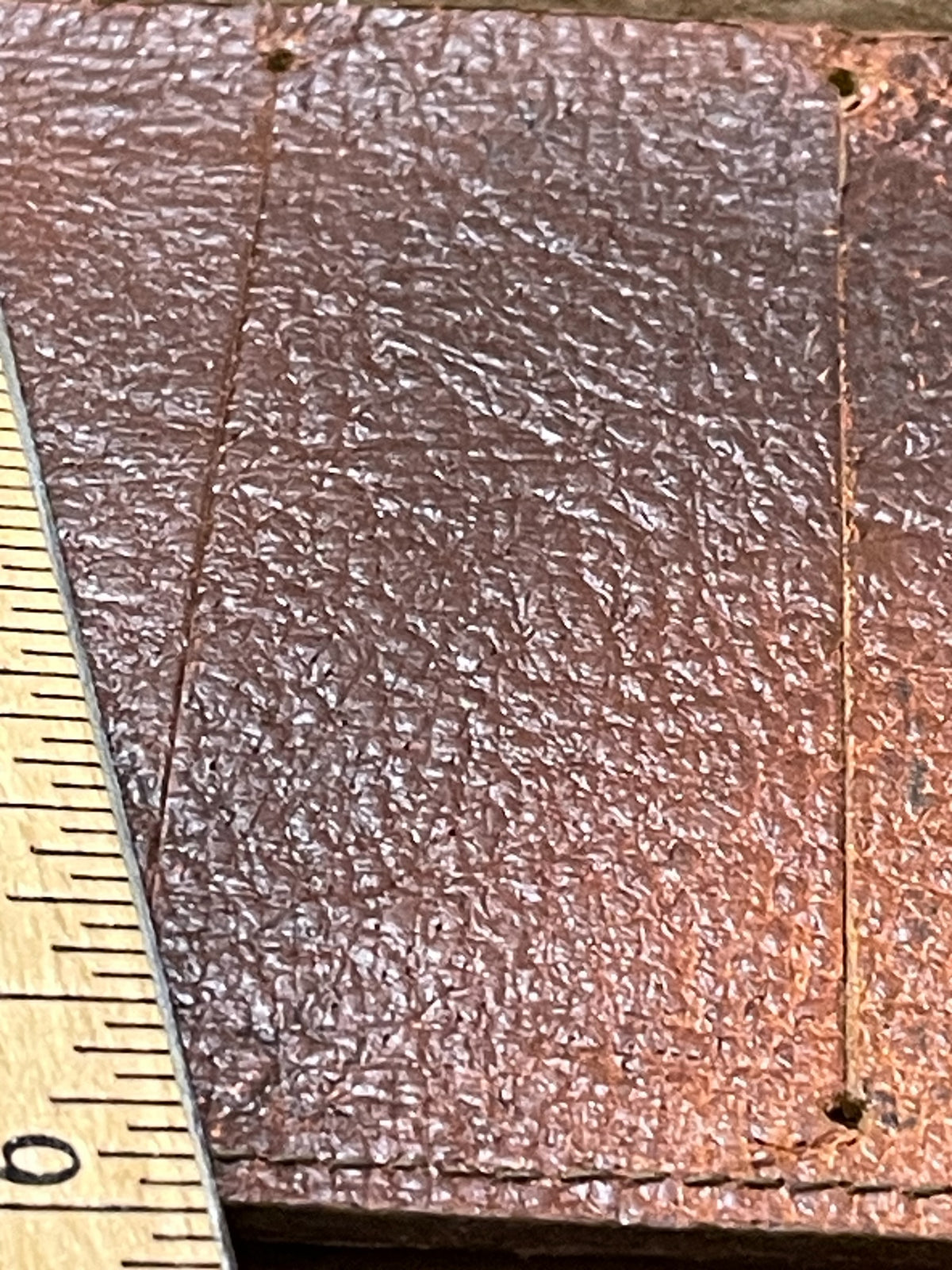 Close-up of brown embossed leather surface and edge on vintage advertising wallet