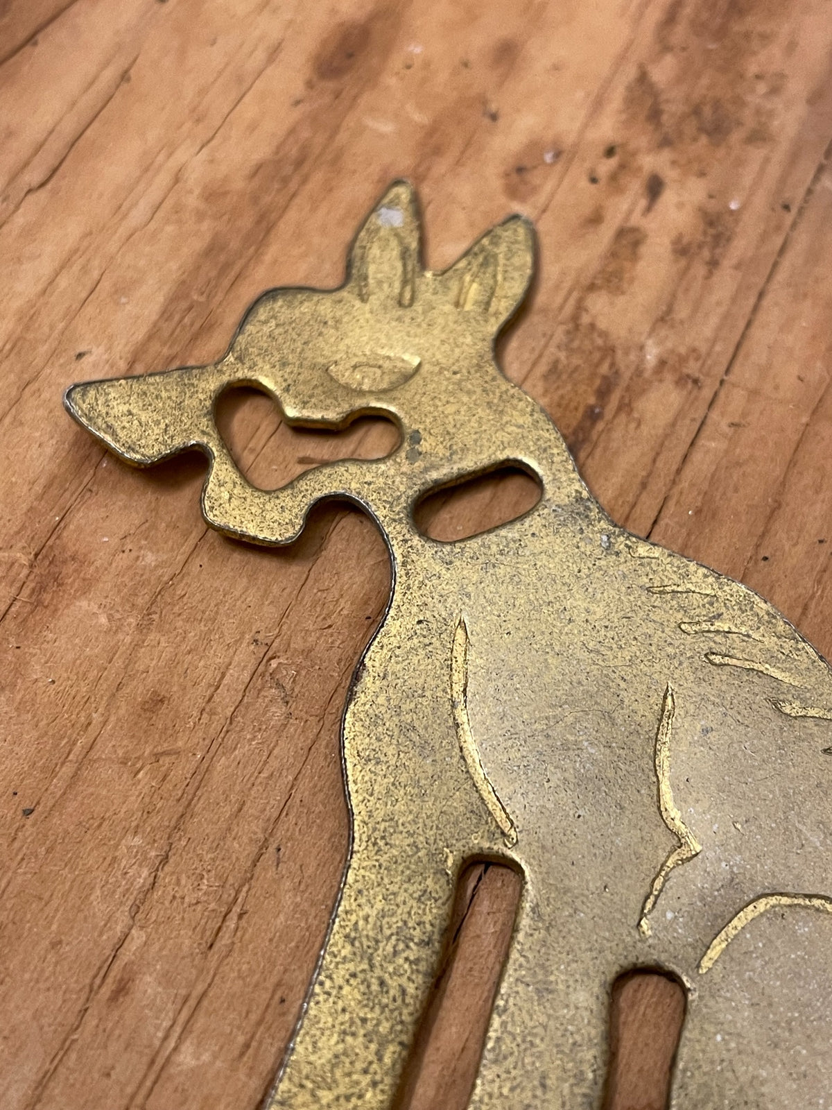 Close-up of unidentified brass-tone dog-shaped figural game piece