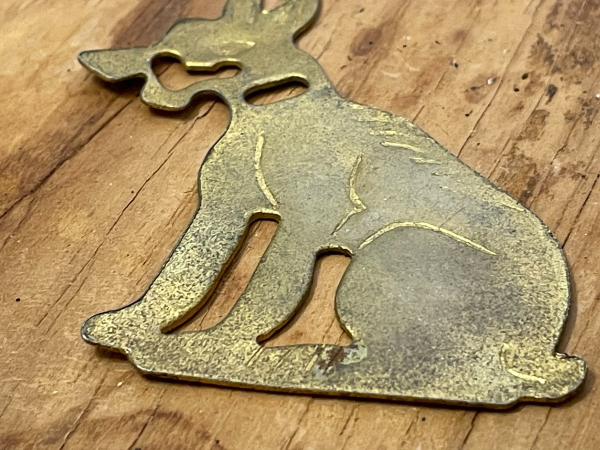 Full view of flat brass-tone dog silhouette game component