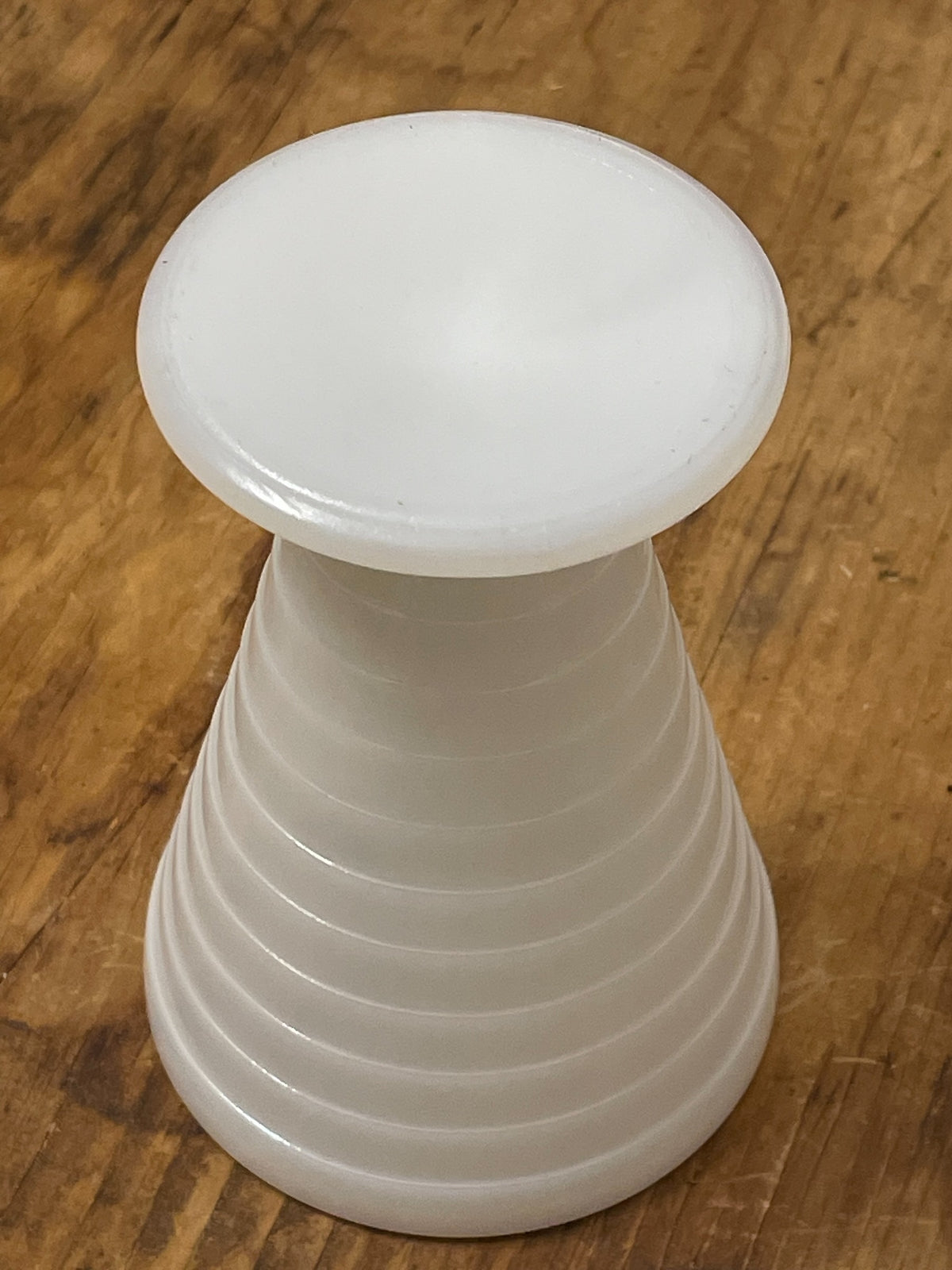Inverted white milk glass cup showing ribbed pedestal form