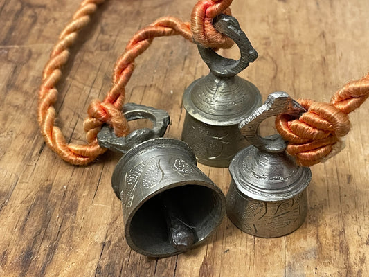 Three decorated brass-tone bells tied on orange cord