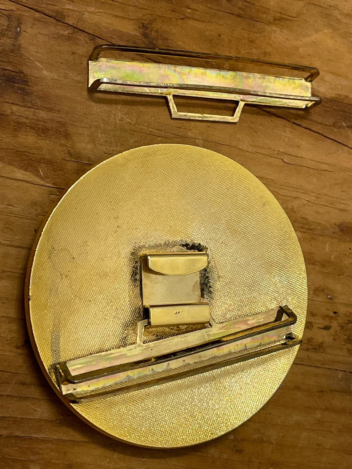 Back of round vintage belt buckle showing brass-tone hardware