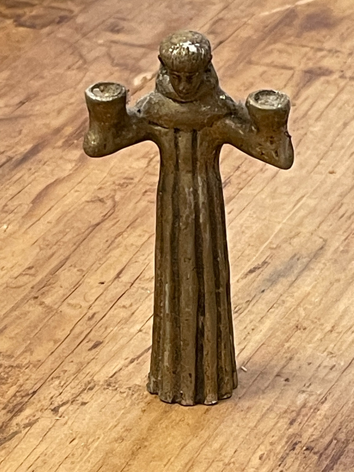 Front view of small vintage cast metal monk or saint figure