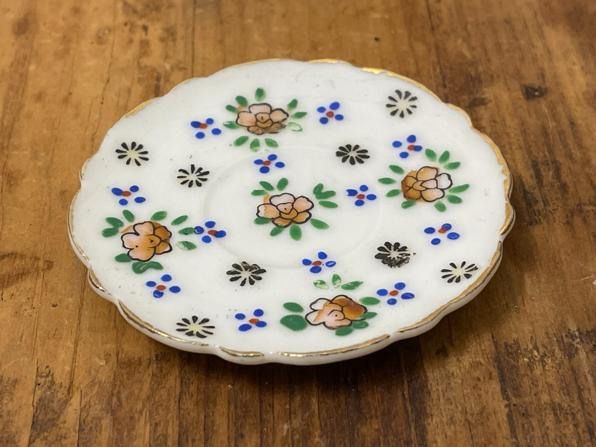 Front view of miniature scalloped porcelain plate with multicolor flowers
