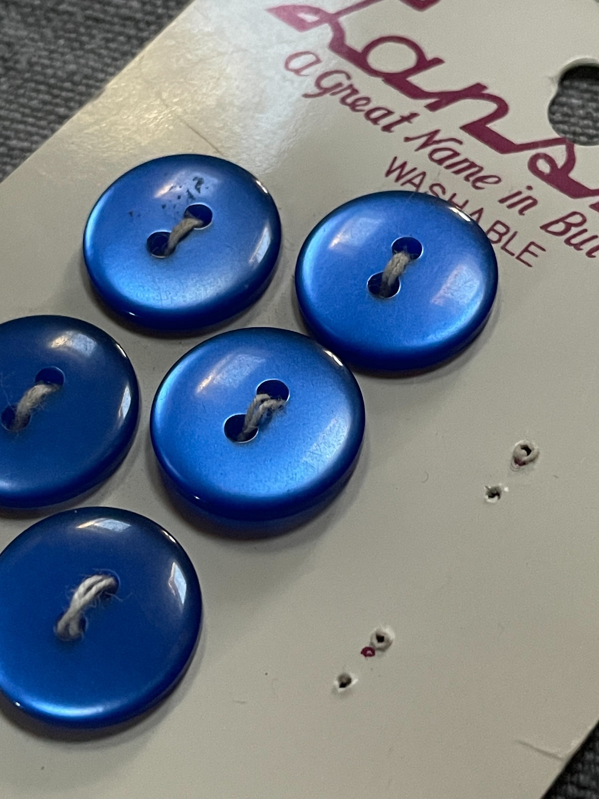 Close-up detail of 6 blue lansing two-hole sewing buttons, 5/8 inch, original card