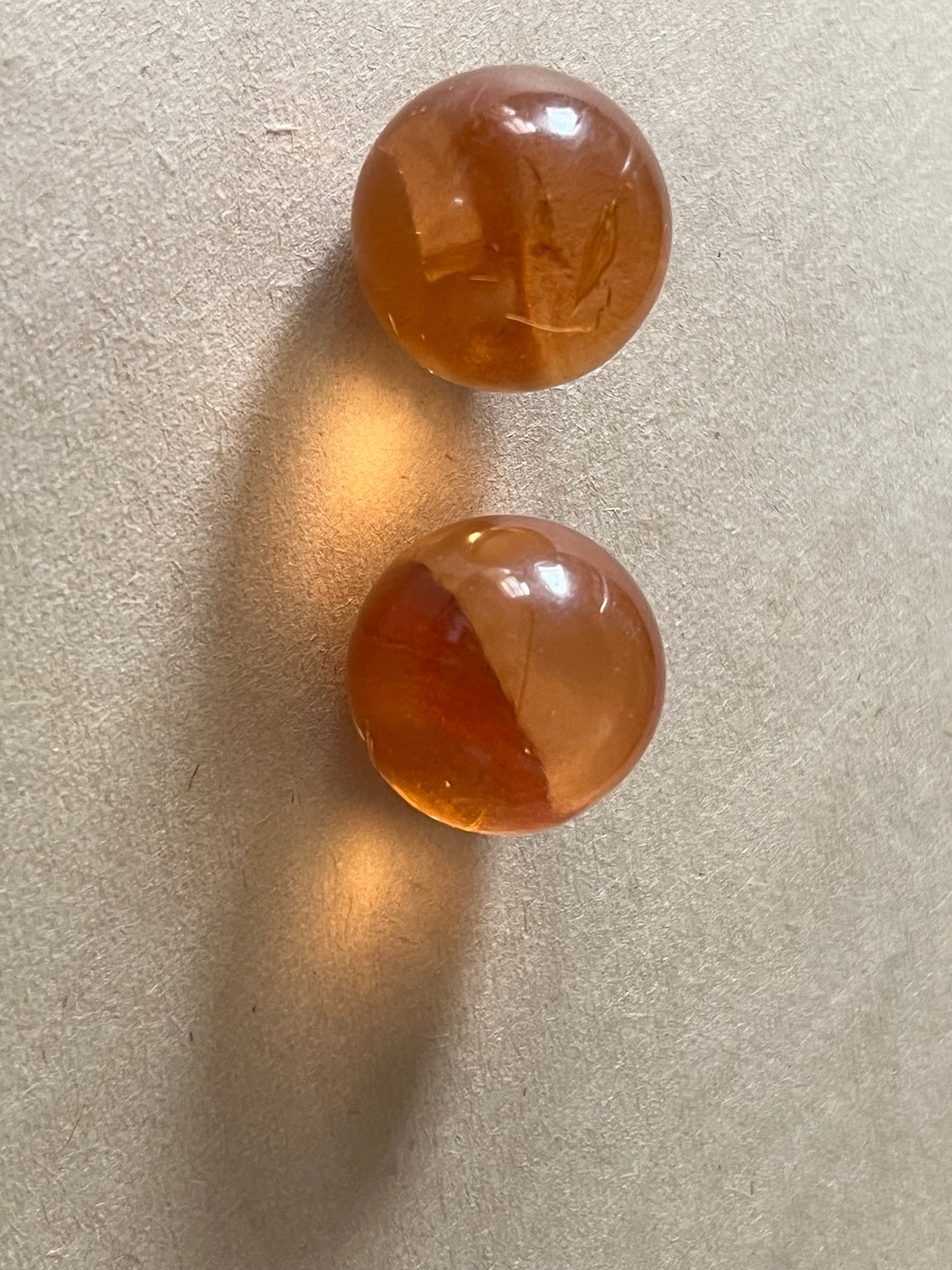 Two translucent amber-brown dome buttons on beige paper.