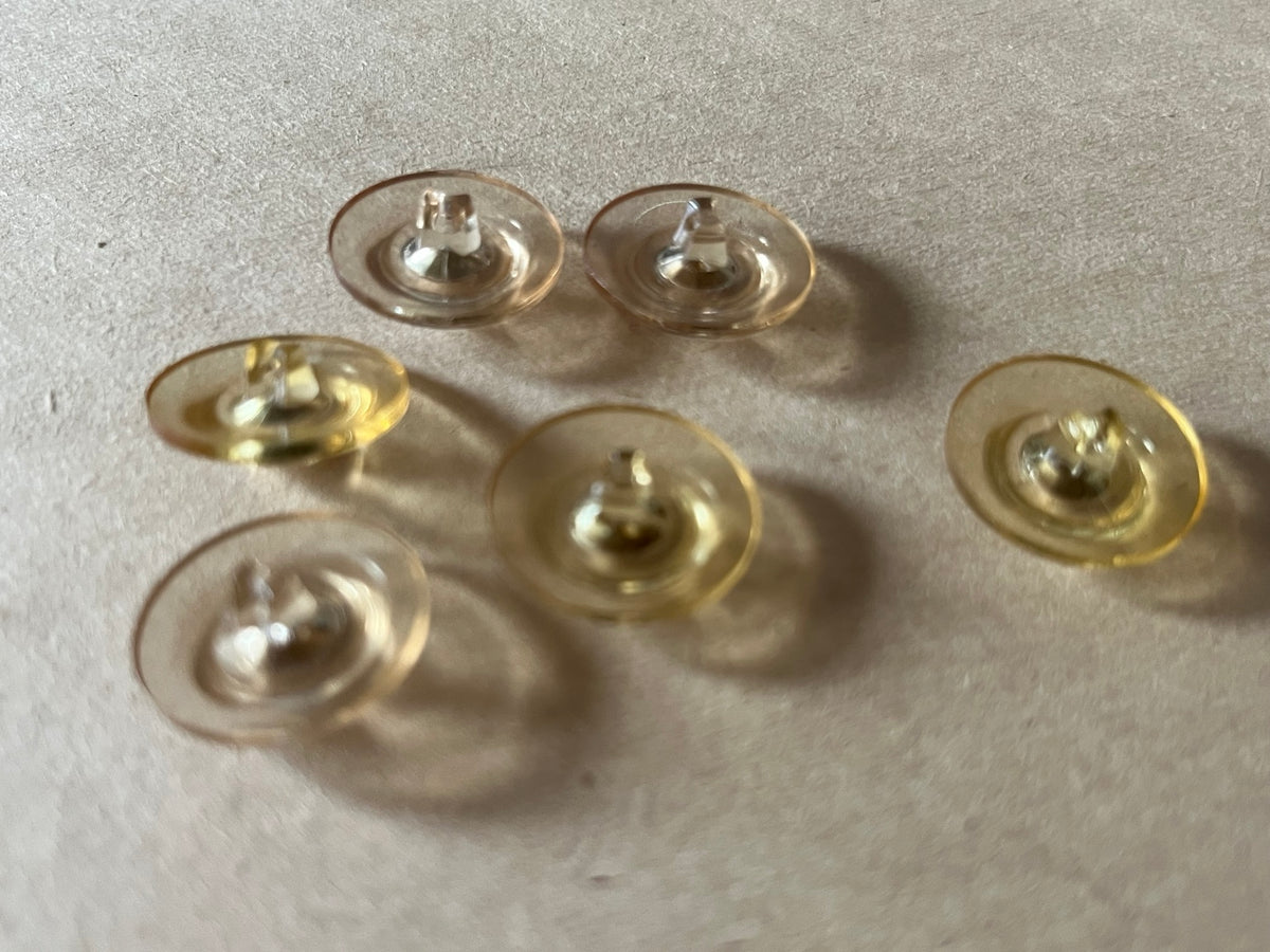 Six translucent pale champagne round buttons with clear faceted centers on beige paper.
