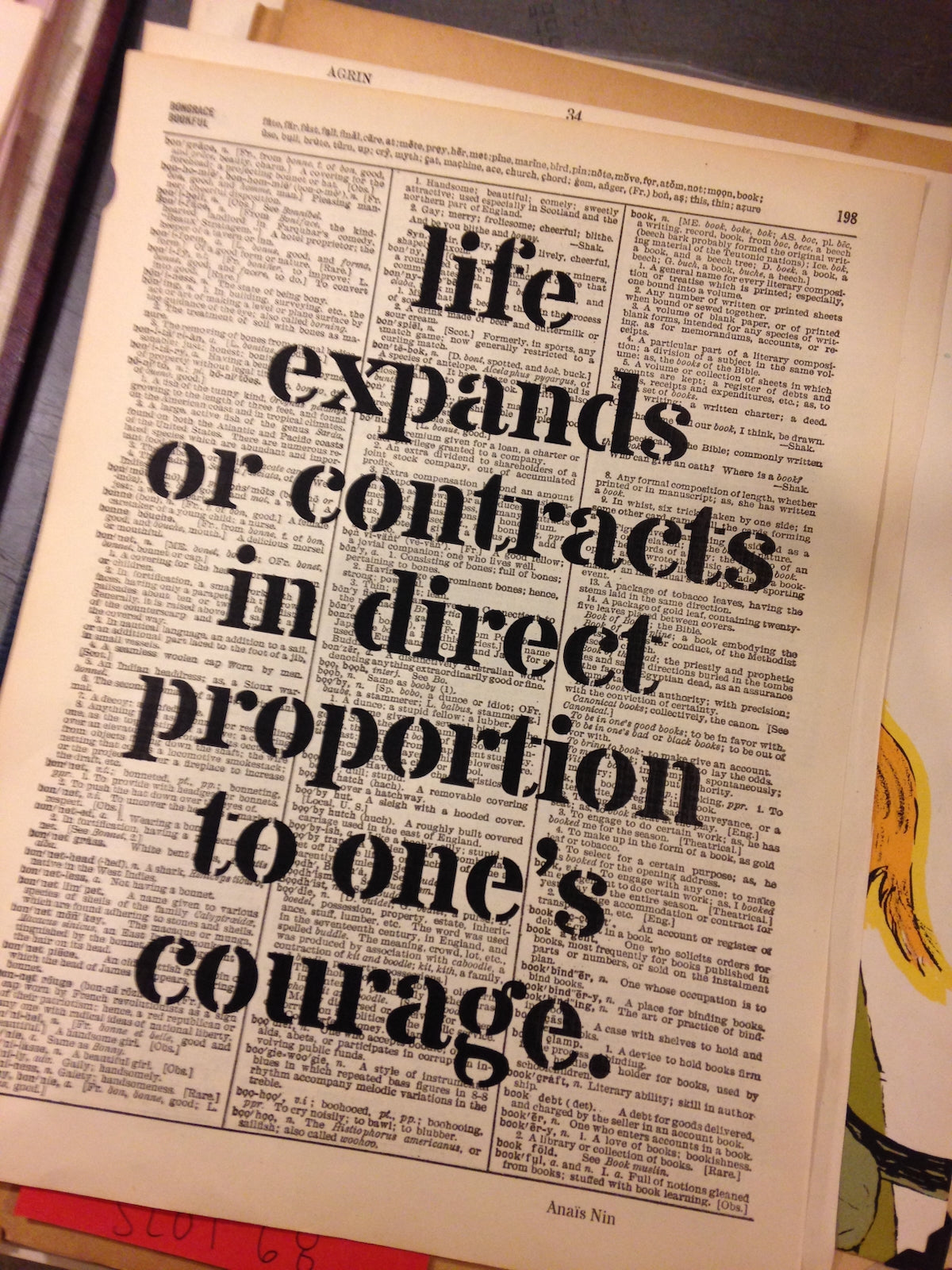 Dictionary page with overprinted motivational quote"life expands or contracts in direct proportion to one's courage."