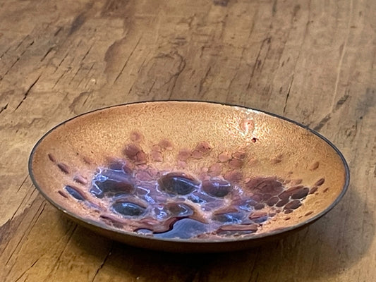 Diminutive enamel on copper bowl against a wooden surface