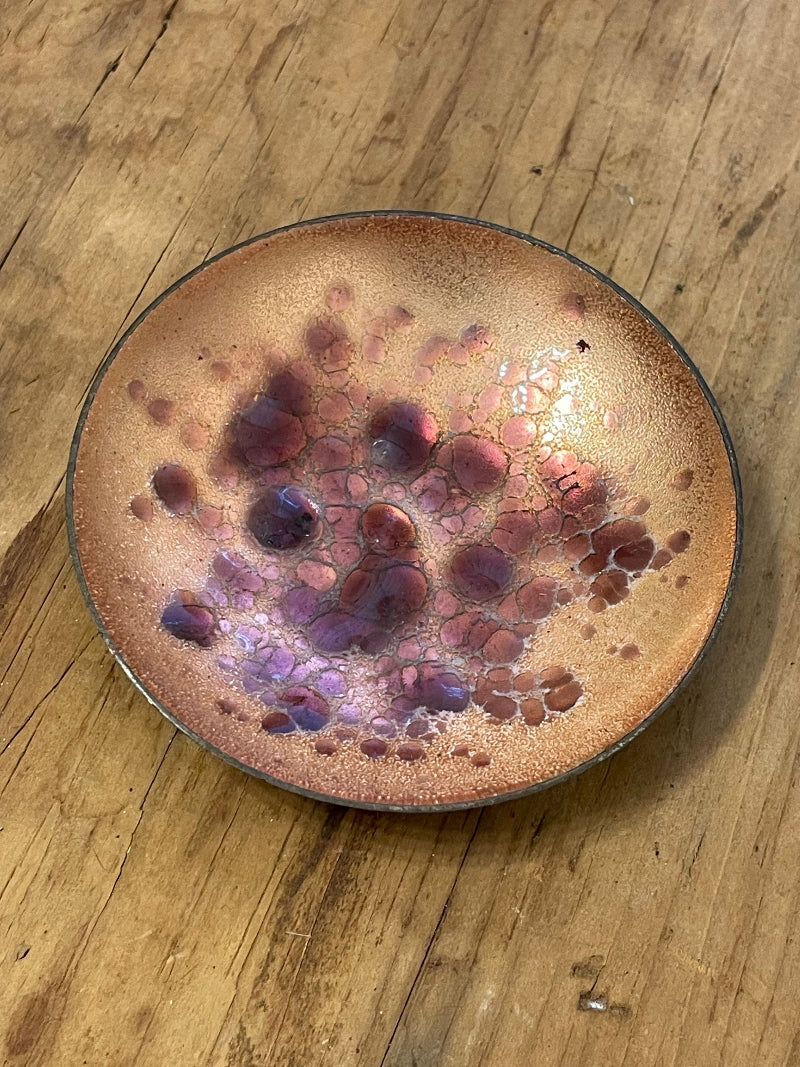 Diminutive enamel on copper bowl against a wooden surface (top view)