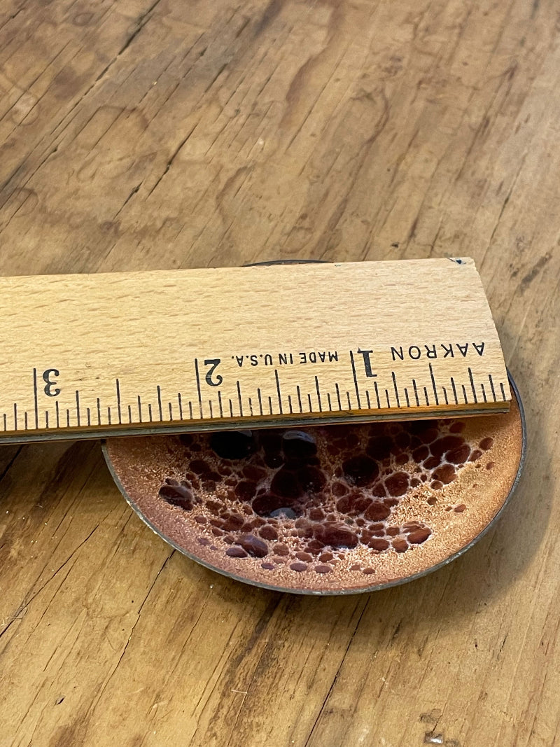 Diminutive enamel on copper bowl and wooden ruler against a wooden surface (bowl is roughly 2.75" in diameter).