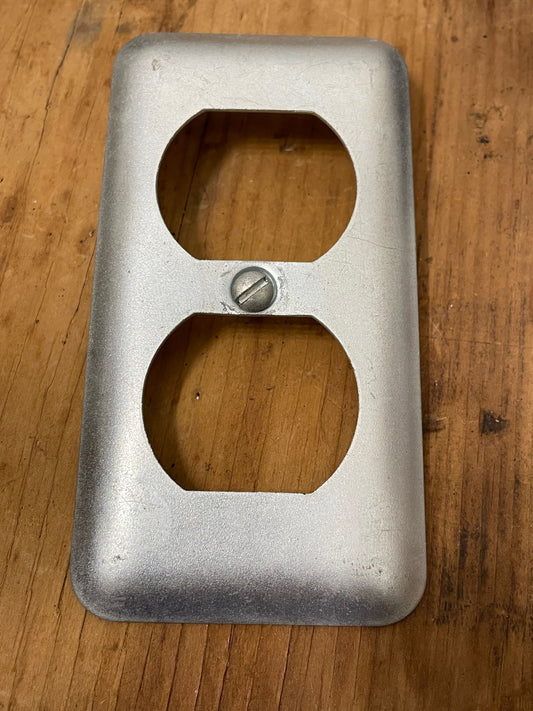 Metal electrical outlet cover on a wooden surface