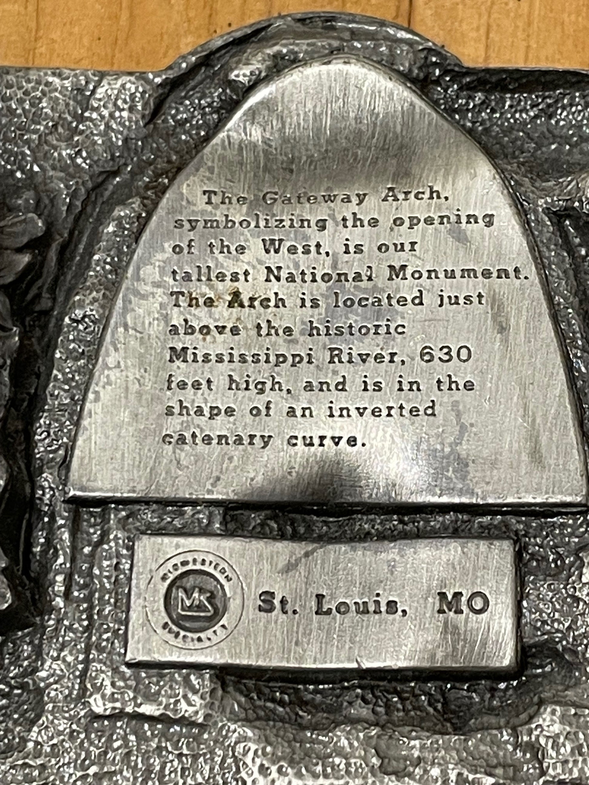 Backside of belt buckle with text about the Gateway Arch in St. Louis, MO