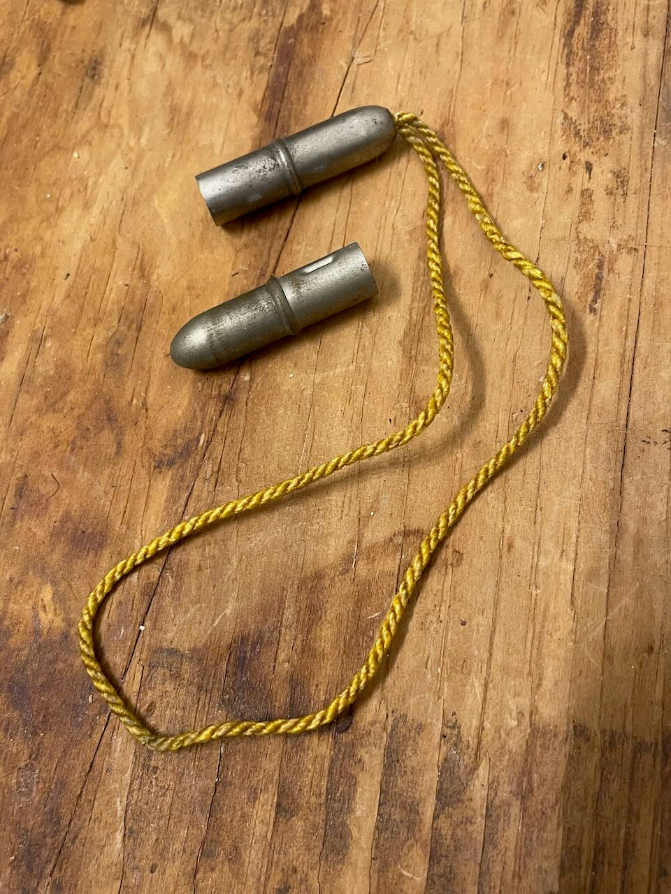 Two vintage metal pencil toppers (one with a cord) on a wooden background.