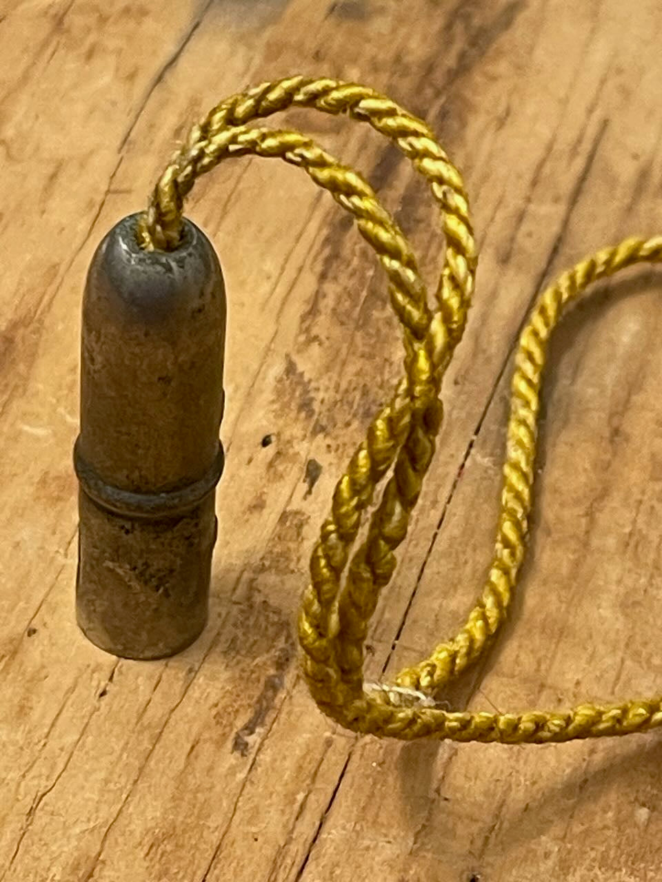 vintage metal pencil topper w/ silk cord on a wooden background.