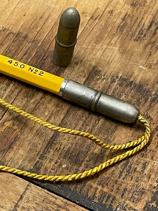 two vintage metal pencil toppers - one obscuring the eraser end of a vintage No. 2 pencil - on a wooden background.