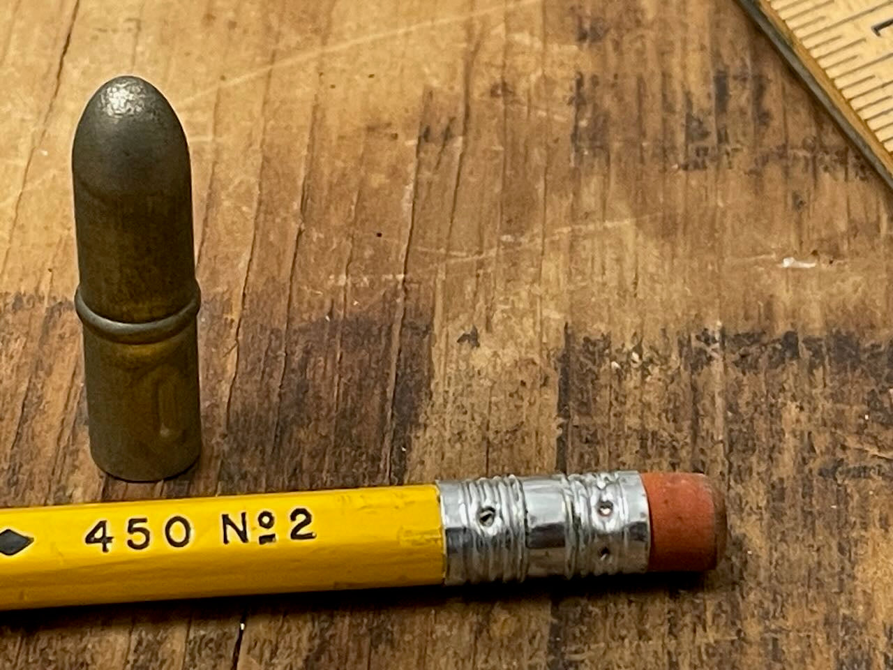 vintage metal pencil topper and the eraser end of a vintage No. 2 pencil on a wooden background.