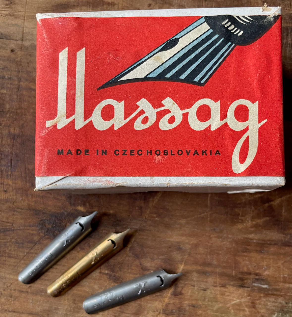 Box of Massag dip pen nibs with three nibs on a wooden surface