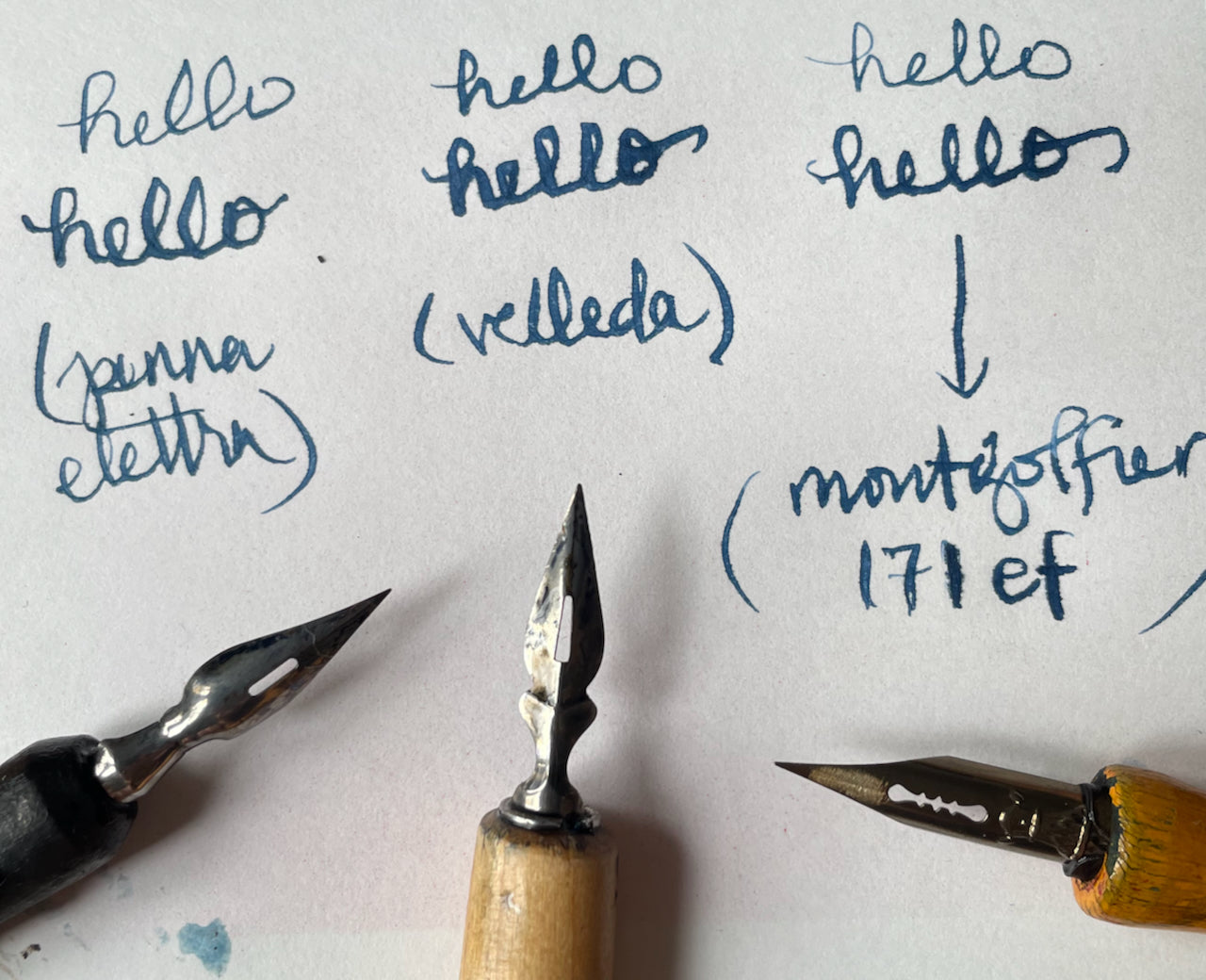 Three nibs from different dip pens with writing samples on a white background